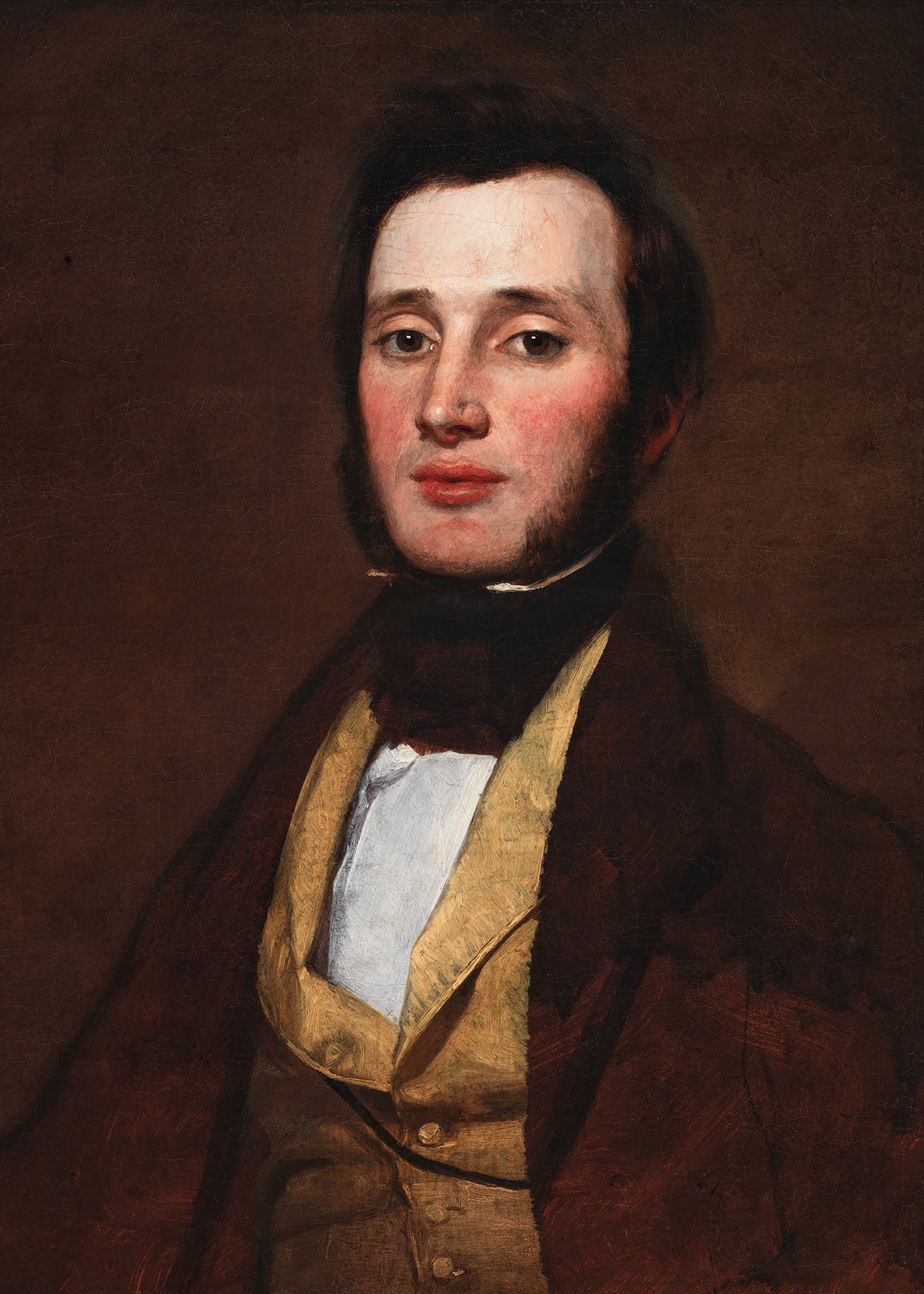 A dark and moody portrait of a young man in a brown jacket and yellow waist coat.&nbsp;